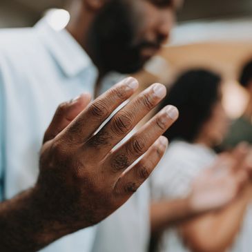 Blurred people with raised hands in a praying gesture.