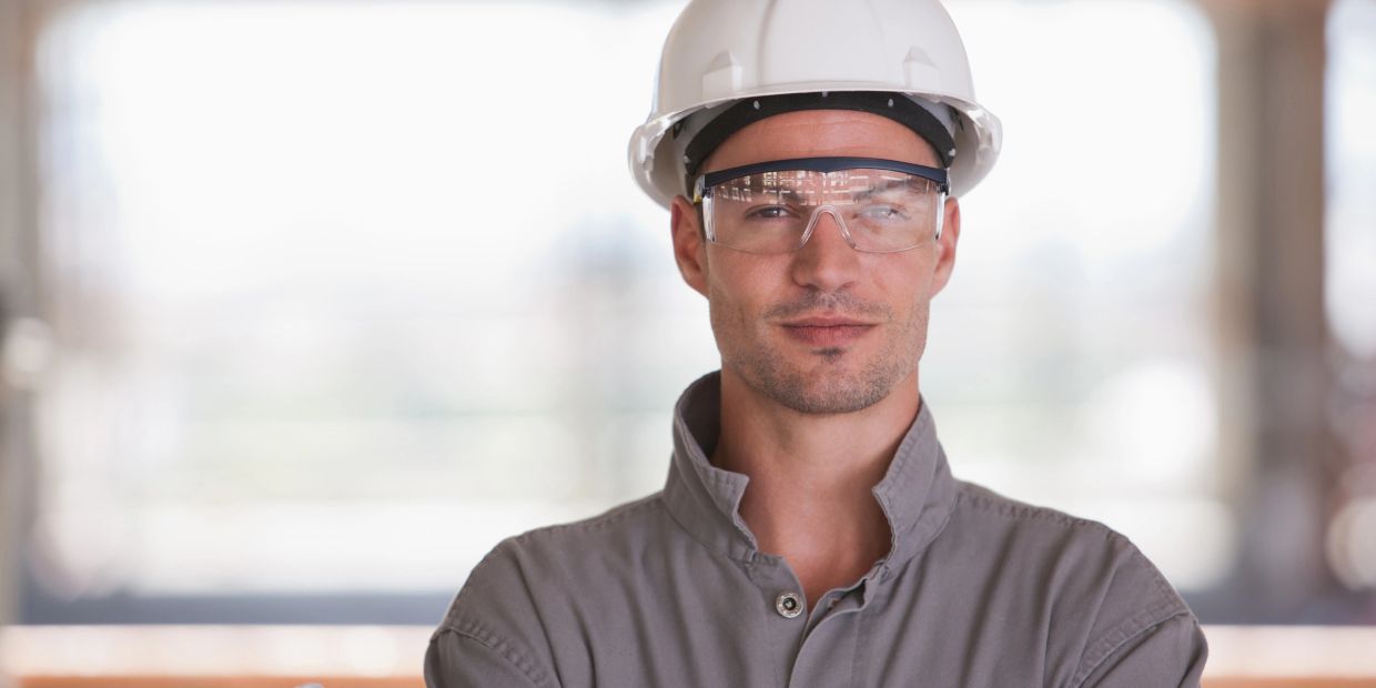 Construction worker wearing safety gear and holding blueprints.