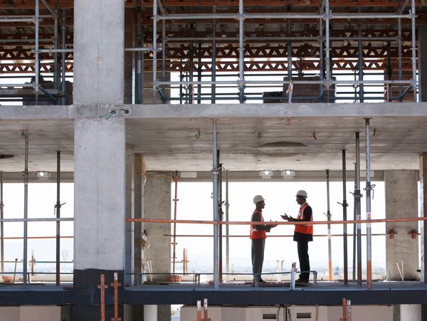 People in business attire standing near a modern glass building.