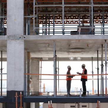 Two construction workers in conversation on a building site.
