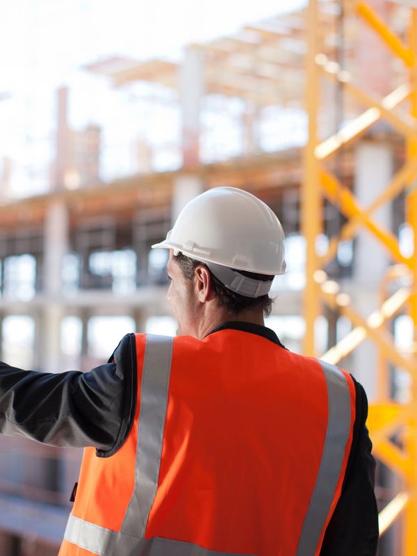 Two construction workers in hard hats and safety vests inspecting site.