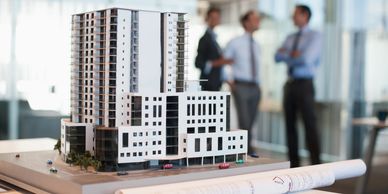 Architectural building model with blueprints and professionals in discussion.