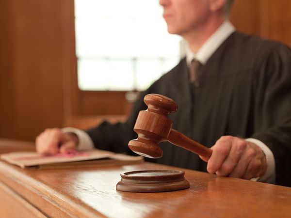 Judge holding a wooden gavel in a courtroom.