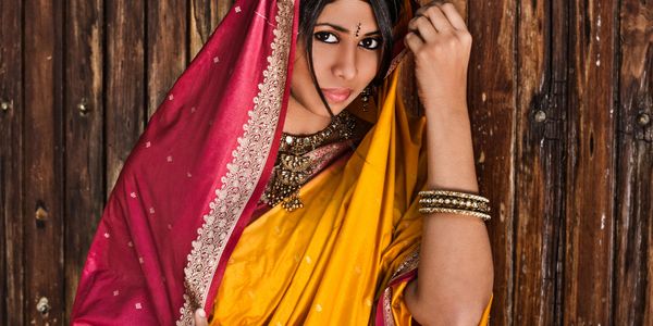 Woman in traditional Indian attire with vibrant yellow and red sari.