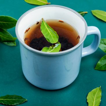 A cup of herbal tea with fresh green leaves.