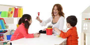 Teacher engaging children in a fun classroom activity with colorful materials.