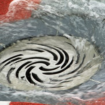 Water whirlpool draining into a metal grate.