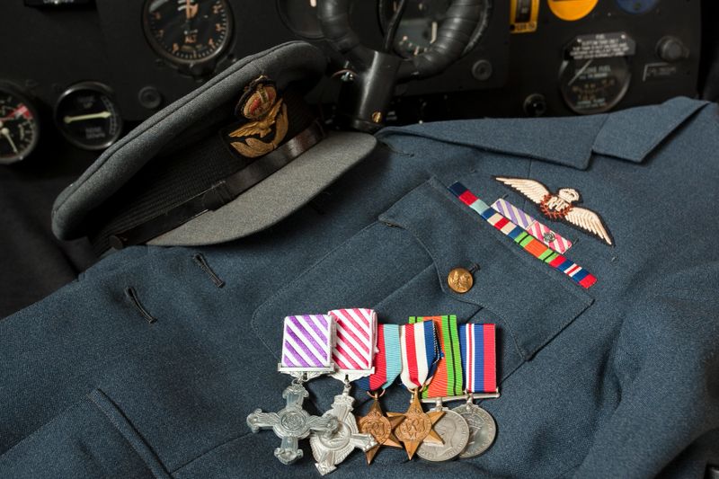 WWII RAF Jacket, Cap and Medals in a Spitfire CockpitShows DFC, AFC, 1939 - 1945 Star, France and Germany Star, Defence Medal and 1939 - 1945 War Medal on a Fighter Pilot Jacket with corresponding medal bars and Queens Crown Pilot Wings. Matching period cap, all displayed inside a Spitfire cockpit with instrument panel and control column.