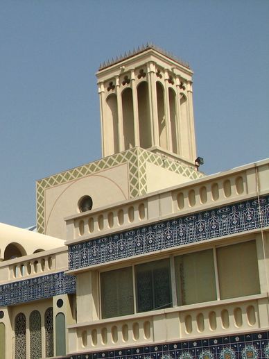 Traditional Middle Eastern wind tower with intricate blue tilework on building facade.