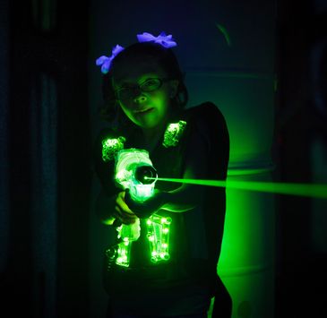 Group of people posing with laser tag guns in a gymnasium.