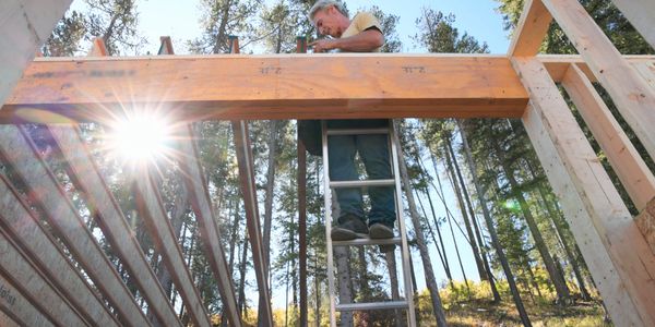 Man working on construction frame outdoors with sun flare.