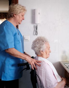 Nurse assisting elderly woman in wheelchair.