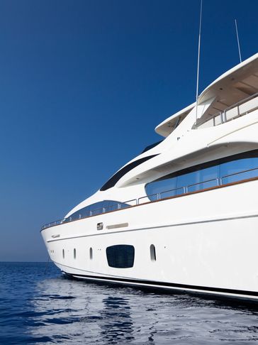 Sleek white yacht floating on calm blue sea under clear sky.