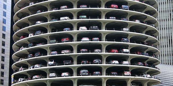 Circular multi-level parking garage filled with cars in an urban setting.
