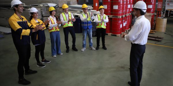 Team in safety gear clapping in industrial setting.