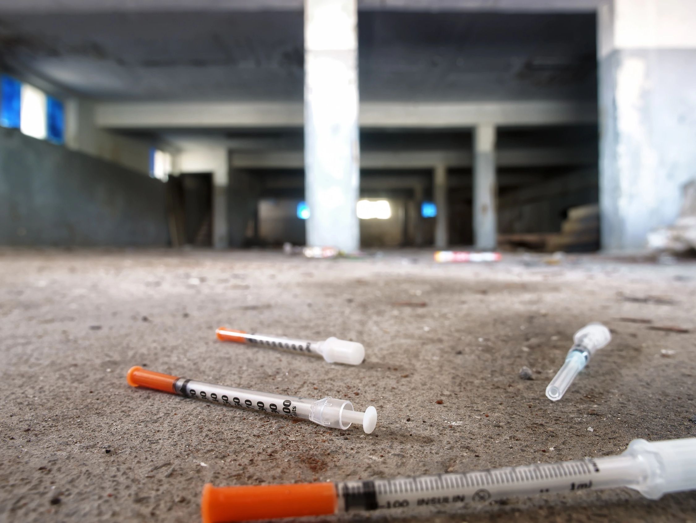 Discarded syringes on the floor of an abandoned building.