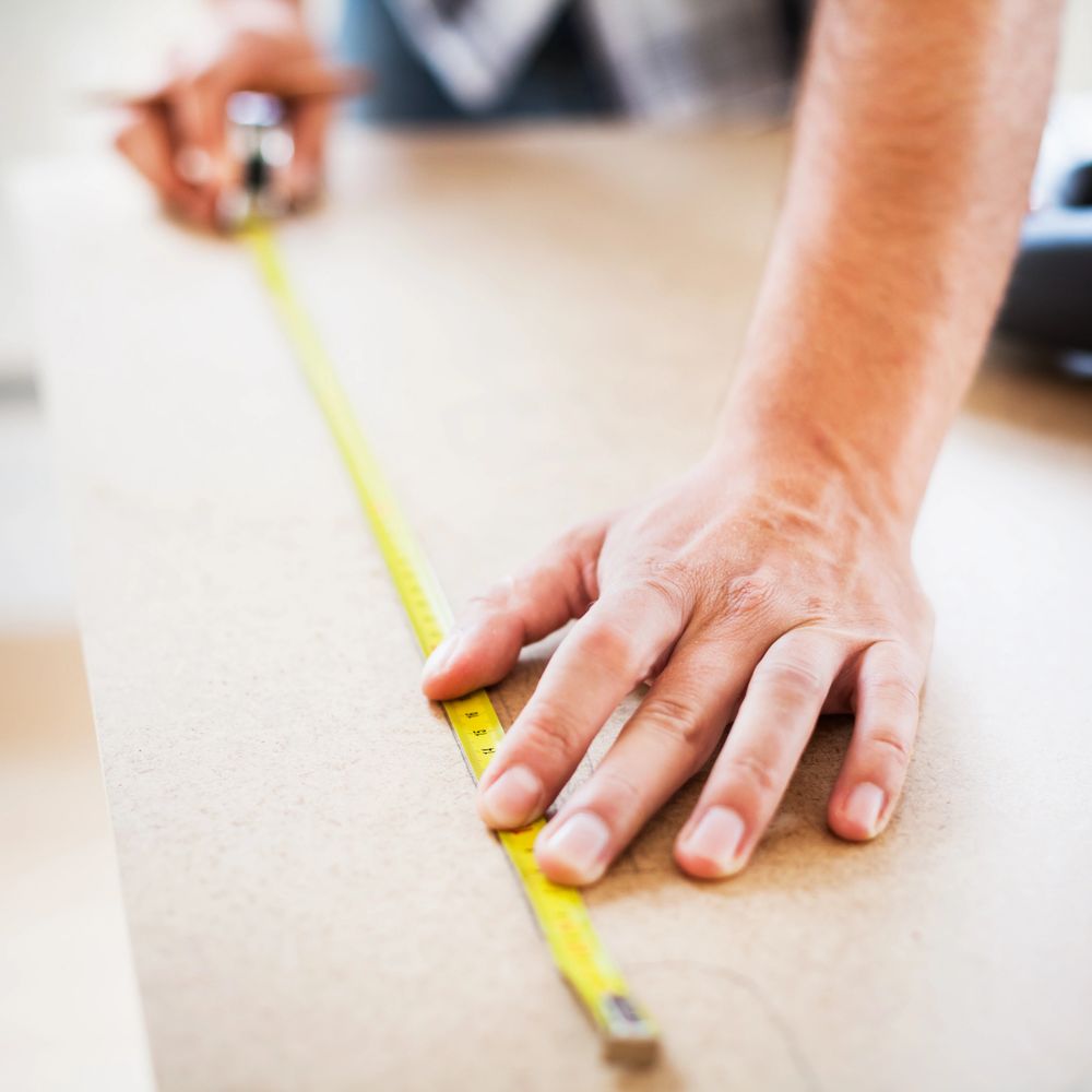 Person measuring wood with a tape measure.
