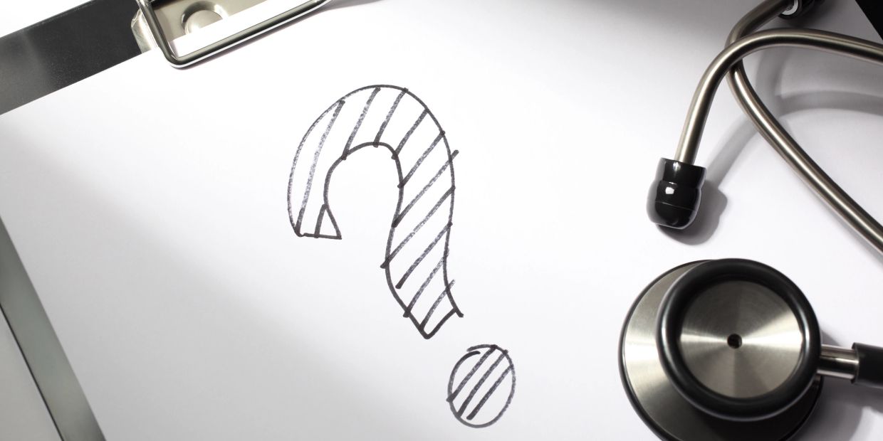 Question mark drawn on medical clipboard with stethoscope.