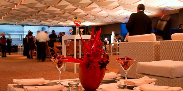 Elegant indoor dining area with red floral centerpiece and guests.