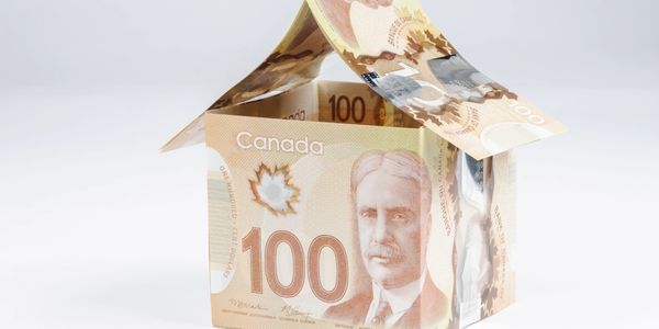 House made of folded Canadian 100-dollar bills symbolizing financial investment or real estate.