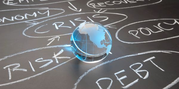 Glass globe on chalkboard with crisis, risk, debt concepts.