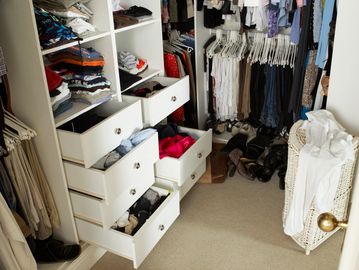 A walk-in closet with open drawers and hanging clothes.