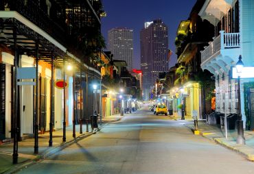Quiet city street at night with illuminated buildings and distant skyscrapers.