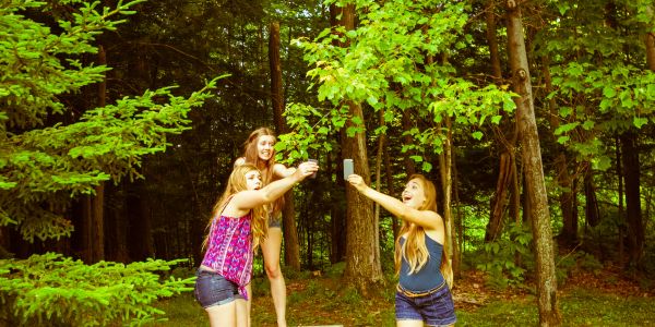 Three girls making a toast in a forest clearing.
