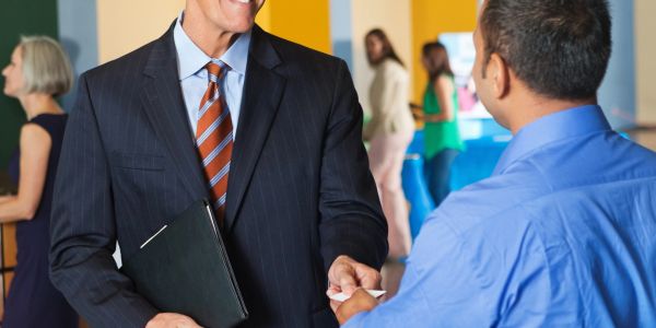 Two men exchanging business cards at a professional event.