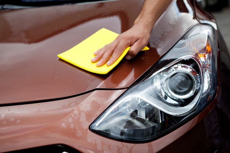 man polishing his car with chamois