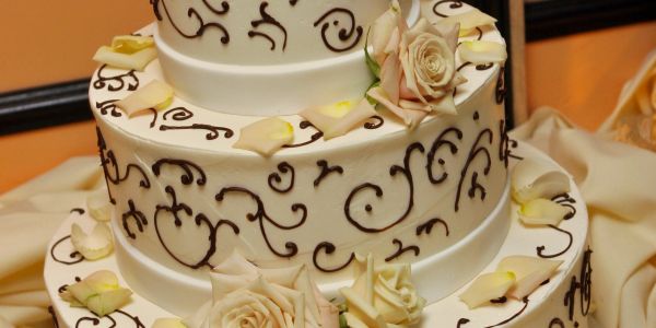Two-tier white cake with roses and chocolate decoration.