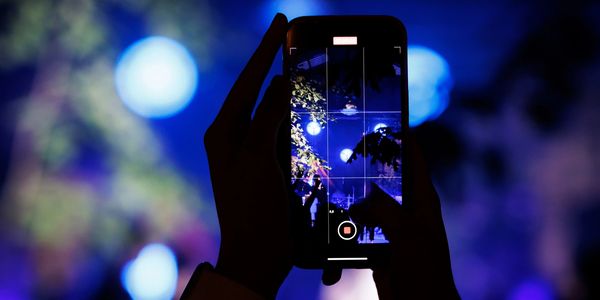 Person recording a bright night scene with a smartphone.