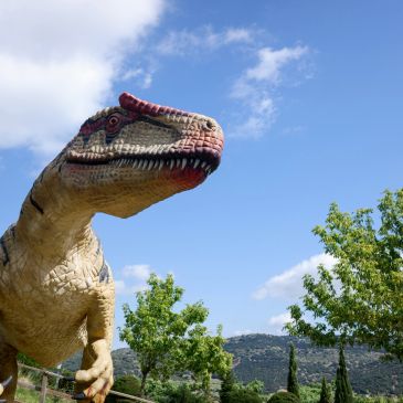 Dinosaur statue against a clear blue sky.