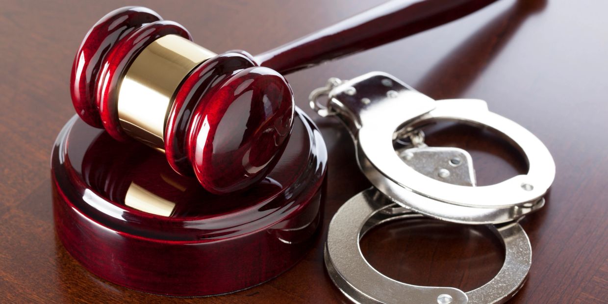 Gavel and handcuffs on a wooden surface.