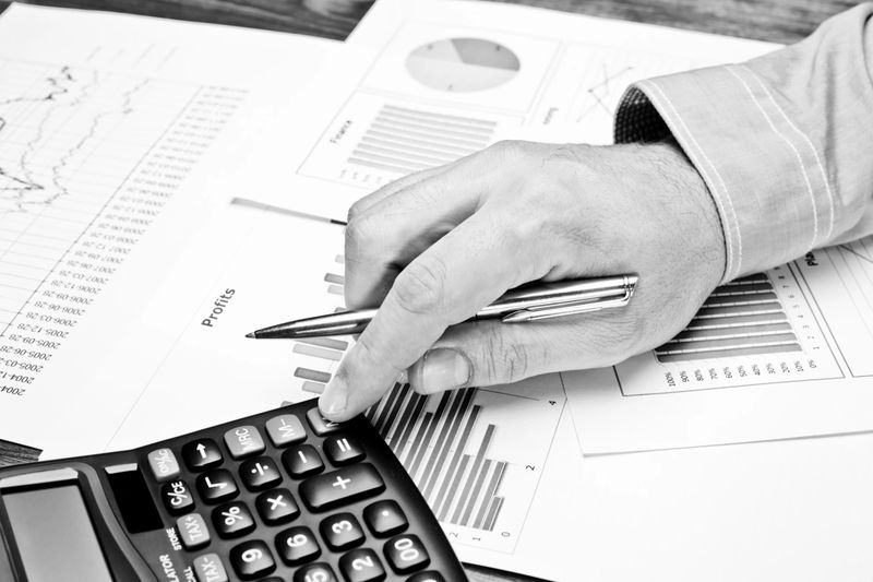 Close-up of male hand with pen working with documents. Black and White