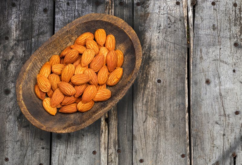 Organic peeled almonds in the wooden bowl - Prunus dulcis