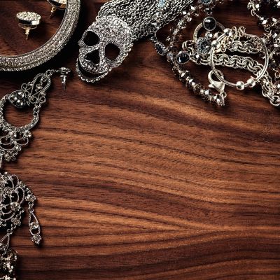 Silver gothic jewelry with skull motifs on wooden surface.