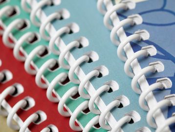 Close-up of spiral bindings on colorful notebooks.