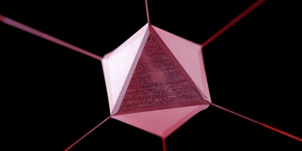Pink geometric prism suspended by strings on a black background.