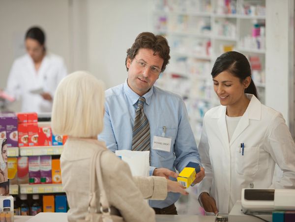 A male and a female pharmacist help an older female customer.








