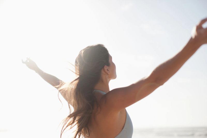 Woman standing with arms outstretched on beach