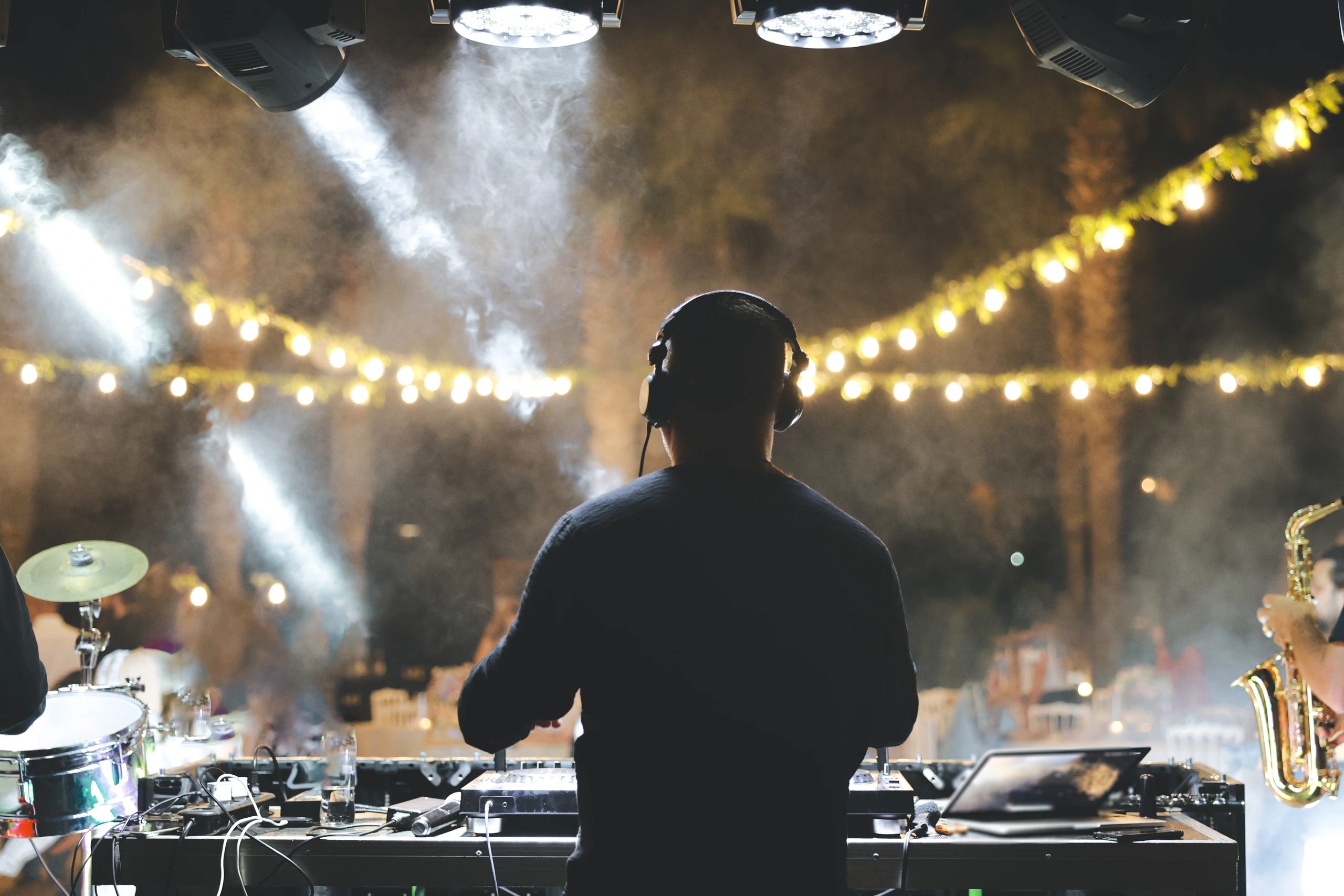 A captivating, low-light photograph of a DJ performing at a nighttime outdoor event or club.