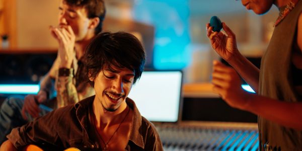 Man playing guitar with friends in a studio.
