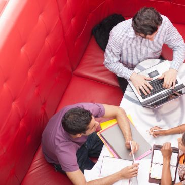 Three people working together with laptops and notebooks.