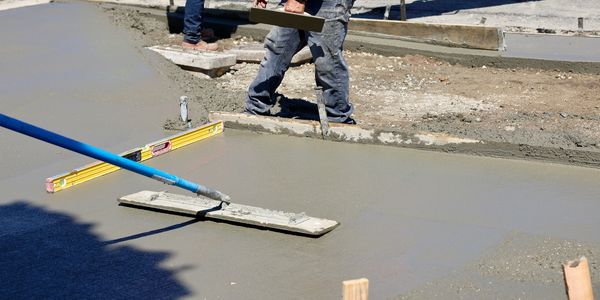 Workers smoothing freshly poured concrete on a construction site.