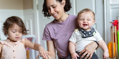 Happy woman with two young children indoors.
