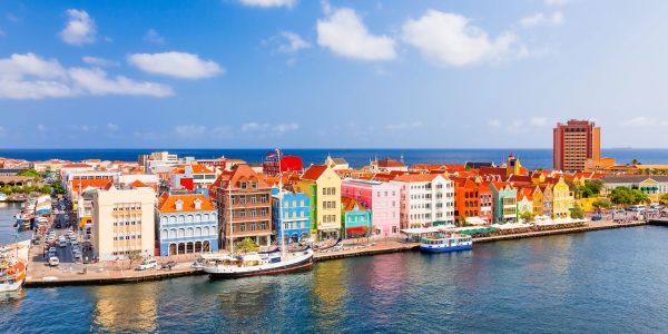 Colorful waterfront buildings in a coastal city under a blue sky.