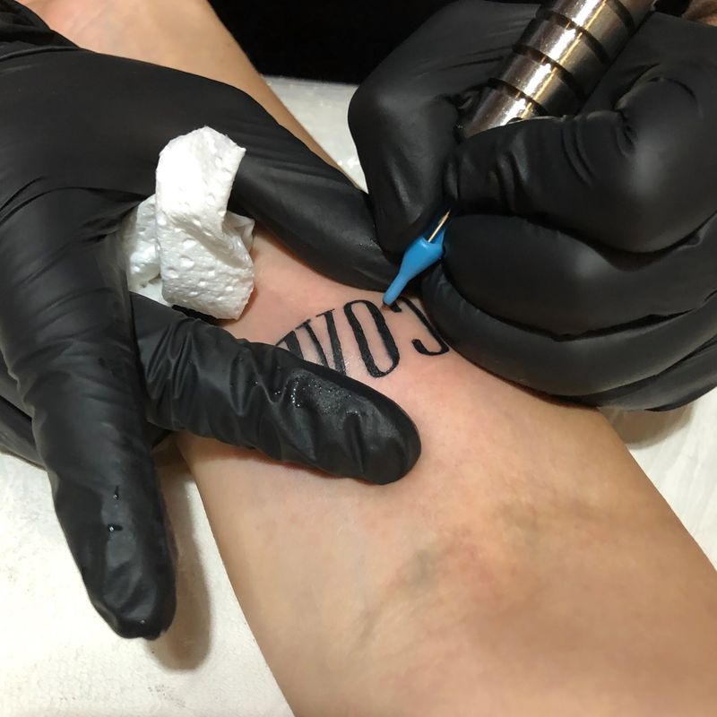A skilled tattoo artist meticulously creates a design on a woman's hand, using a tattoo machine to deposit ink, resulting in a beautifully adorned hand.