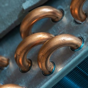 Close-up of curved copper pipes on a metallic surface.