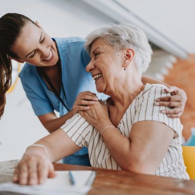 A nurse warmly comforting an elderly woman with a smile.